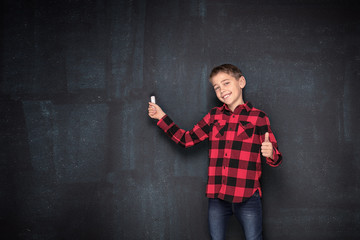 Teenage boy in checkered shirt over black chalk board.