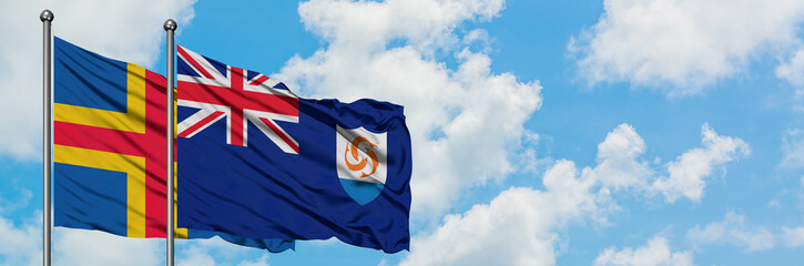 Aland Islands and Anguilla flag waving in the wind against white cloudy blue sky together. Diplomacy concept, international relations.