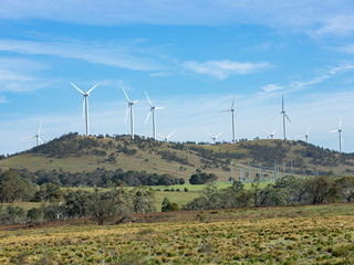 An array of large wind turbines moving to create kinetic energy for renewable energy supply on a...