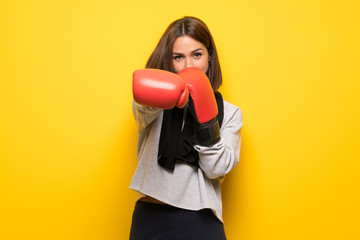 Young sport woman over yellow background with boxing gloves