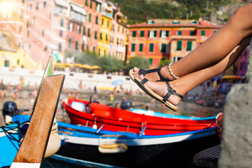 Legs of a woman with sandals at the view of Cinque Terre