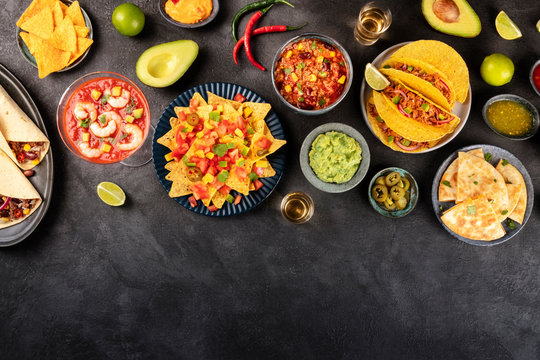 Mexican food, many dishes of the cuisine of Mexico, flat lay, shot from the top on a black background with a place for text. Nachos, tequila, guacamole etc
