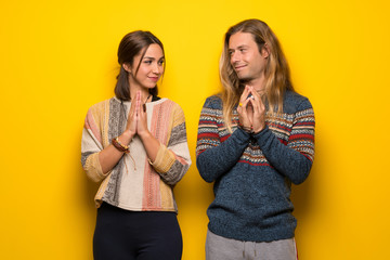 Hippie couple over yellow background scheming something