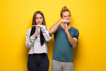 Group of athletes over yellow background making stop gesture with her hand to stop an act