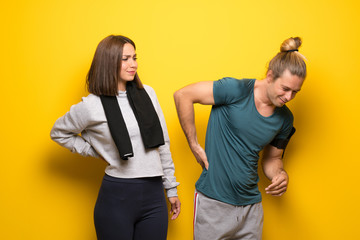 Group of athletes over yellow background suffering from backache for having made an effort