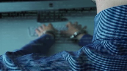 Man in business shirt wearing a handcuffs, typing on a keyboard. Concept: workaholic, prisoner of a computer, internet addiction,  death notice, time is running, waste of time - Powered by Adobe