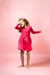 Funny dancing little girl. Real emotions and expression. Pink palette. The concept of childhood, fun, children's party, holiday.