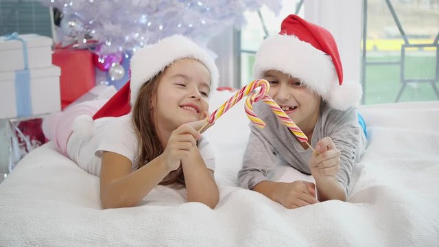 Warm Christmas atmosphere in which joyful sister and brother playing with candy canes, imitating a swordfight. Sister's candy gets broken and she started to cry.