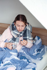 Student is lying at home in bed with flu symptoms. girl takes medicine