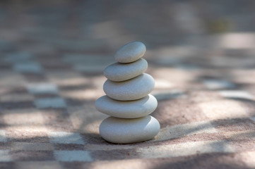 Fototapeta na wymiar Harmony and balance cairns, simple poise stones on white and brown textile checkered background