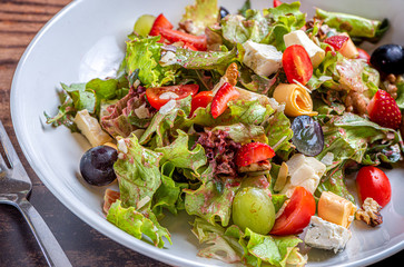 Gourmet green salad with cheese, grape, strawberries and cherry