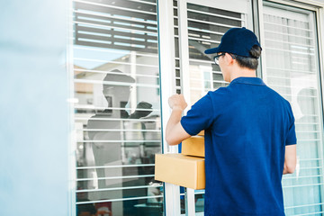 Delivery Asian man service with boxes in hands standing in front of Customer's house doors