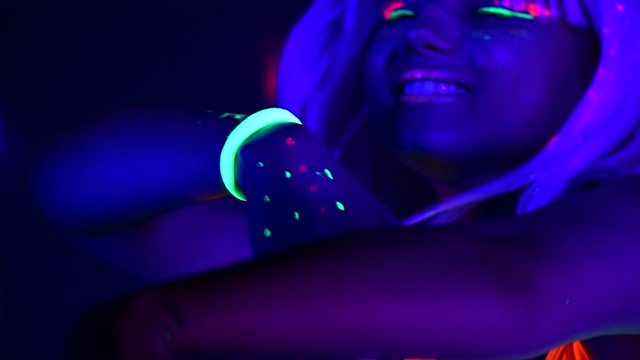 Fashion model dancing woman in neon light, beautiful model girl colorful bright fluorescent make-up, painted skin, Body Art design, disco female in UV, colorful make up. Night club. Slow motion 4K UHD