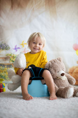 Cute toddler boy, potty training, playing with his teddy bear