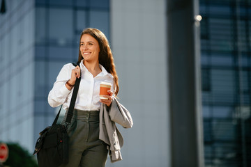 Portrait of young woman walking on the street with coffee