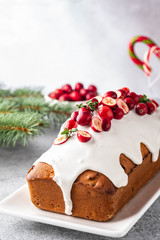 Christmas cake with cranberries and Christmas decorations on a gray background.