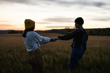 Happy young couple dressed casual in a sunset. Girl and guy kissing
