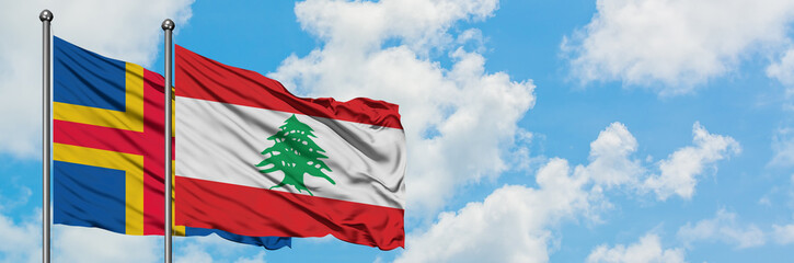 Aland Islands and Lebanon flag waving in the wind against white cloudy blue sky together. Diplomacy concept, international relations.