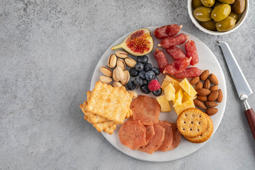 Meat and cheese plate.Traditional italian antipasto, cutting board with salami, cold smoked meat, prosciutto, ham, cheeses, olives, capers on white background. Cheese and meat appetizer. Top view.