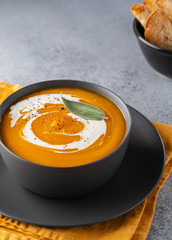 Pumpkin soup with cream on grey stone background. Copy space.