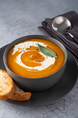 Pumpkin soup with cream on grey stone background. Copy space.