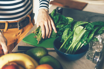The process of preparing food for cooking dinner. Sliced ​​spinach. Female hands. Kitchen care.
