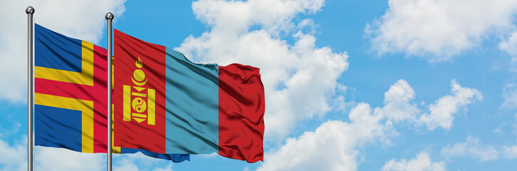 Naklejka premium Aland Islands and Mongolia flag waving in the wind against white cloudy blue sky together. Diplomacy concept, international relations.
