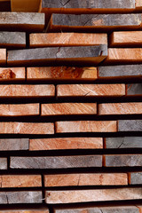 Abstract natural background. Side view on slices of folded boards. Natural drying of wooden boards. Horizontal lines. Close-up, vertical, cropped shot. Concept of woodworking and construction.