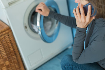 A woman calls a repair service for a breakdown of a washing machine. 