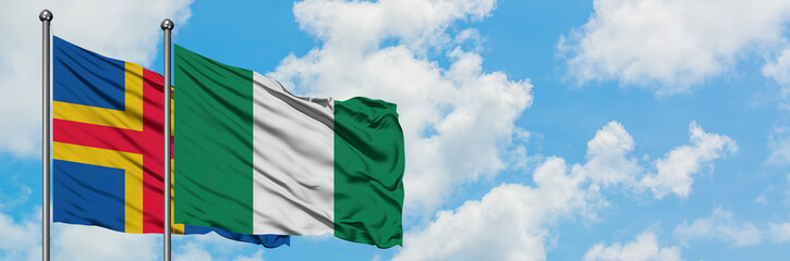 Aland Islands and Nigeria flag waving in the wind against white cloudy blue sky together. Diplomacy concept, international relations.