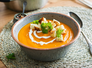 Pumpkin soup in a bowl served with parsley and croutons. Vegan soup. Thanksgiving day food. Halloween meal.