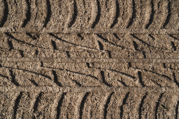 Tire tread of the car in the sand. Closeup. Brown background