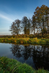 Quiet river in beautiful autumn landscape with reflection