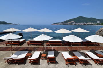 beach in resort area with white umbrellas in Budva, Montenegro