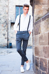 Obraz premium young European guy in shirt and trousers with suspenders walking around city