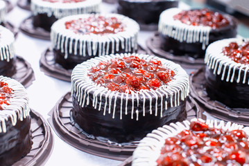 Many beautiful and delicious chocolate cakes with fresh cherry and cream. Confectionery production...