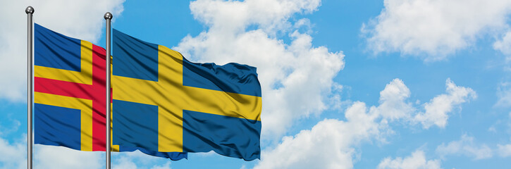 Aland Islands and Sweden flag waving in the wind against white cloudy blue sky together. Diplomacy concept, international relations.