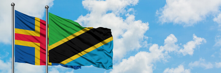 Aland Islands and Tanzania flag waving in the wind against white cloudy blue sky together. Diplomacy concept, international relations.