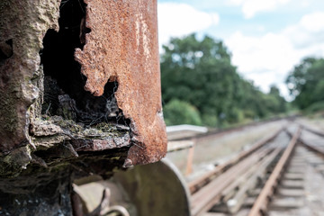 Shallow focus view of an abandoned British goods train in an advanced state of decay, with a view down a railway track located on a siding in the UK.