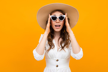 middle-aged brown-haired woman holds sunglasses in hands on a yellow background