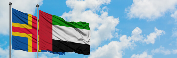 Aland Islands and United Arab Emirates flag waving in the wind against white cloudy blue sky together. Diplomacy concept, international relations.