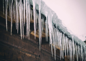 Icicles hanging from the roof of the old, rustic house.