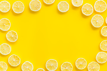 Lemon slices frame on yellow background top view copy space