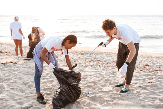 Image of active volunteers cleaning beach from plastic with trash bags