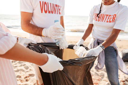 Photo of young volunteers teamwork cleaning beach from plastic together