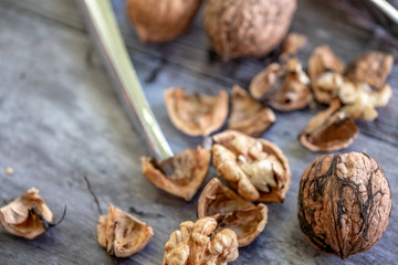 Close-up, shallow focus image of freshly cracked Walnuts seen with a metal Nutcracker. Fragments of...