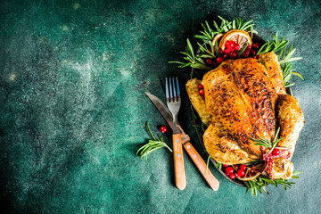 Traditional Christmas and Thanksgiving roasted whole chicken with fruit and rosemary. Dark green...