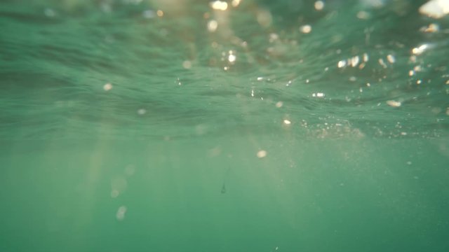 Underwater, sea waves with sunrays shining through the water