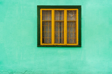 Fototapeta na wymiar Yellow window with bars on blue wall