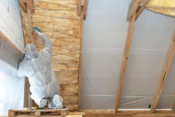 Professional foreman installing thermal insulation rock wool under the roof